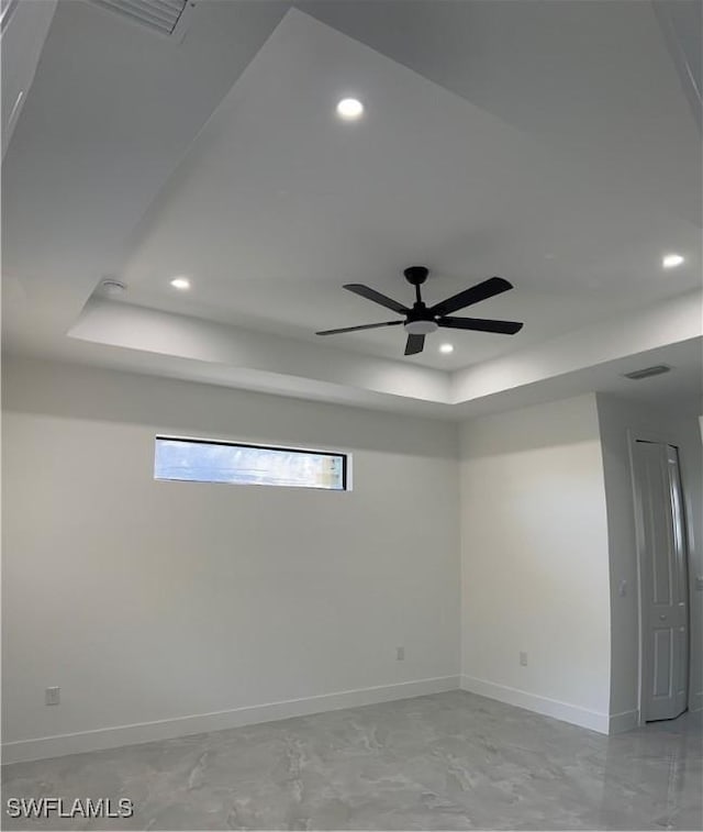 unfurnished room with ceiling fan and a raised ceiling