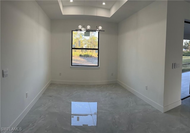 unfurnished dining area with a notable chandelier and a tray ceiling