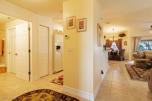 hallway with light tile patterned floors and a notable chandelier