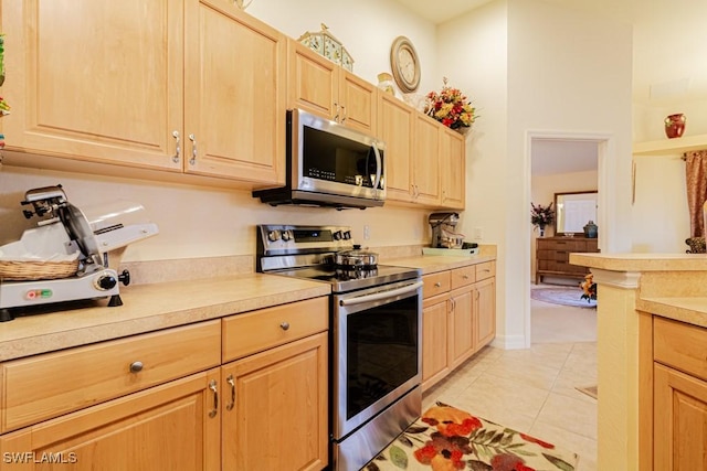 kitchen with appliances with stainless steel finishes, light brown cabinets, and light tile patterned floors