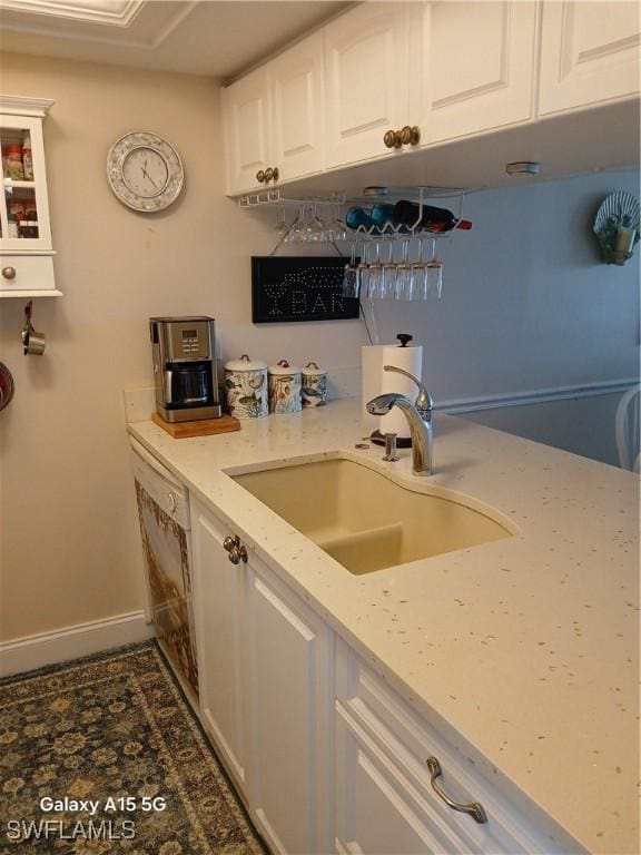 kitchen featuring white cabinetry, sink, dishwasher, and light stone counters