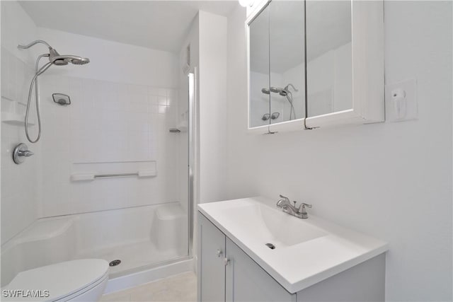 bathroom with tiled shower, tile patterned floors, vanity, and toilet