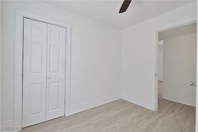 unfurnished bedroom featuring ceiling fan, light wood-type flooring, and a closet