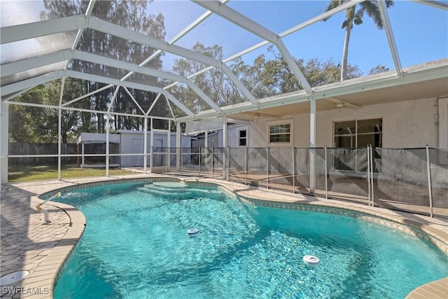 view of pool with glass enclosure, a patio area, and a storage shed