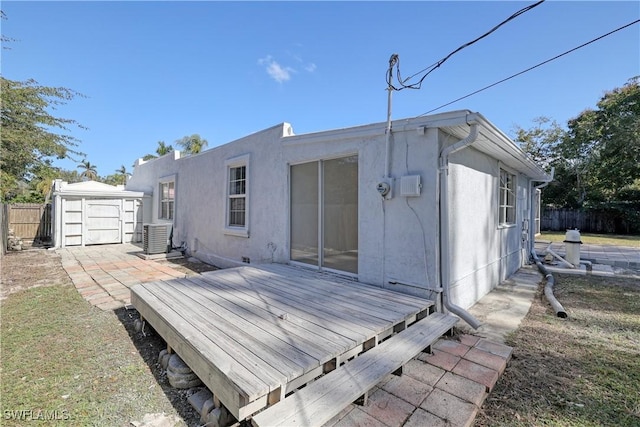 back of property with a wooden deck and a storage unit