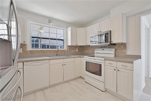 kitchen featuring white cabinets, sink, appliances with stainless steel finishes, and tasteful backsplash