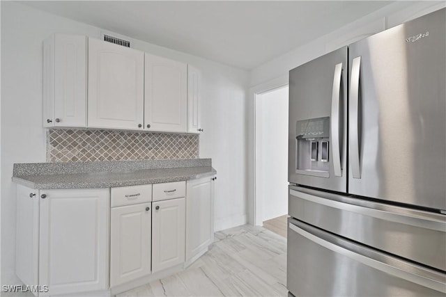 kitchen featuring stainless steel fridge with ice dispenser, tasteful backsplash, and white cabinetry