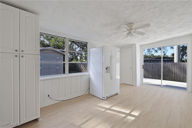 unfurnished room with ceiling fan, light wood-type flooring, and a textured ceiling