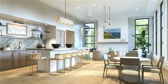 kitchen with gray cabinets, a breakfast bar, decorative light fixtures, sink, and backsplash