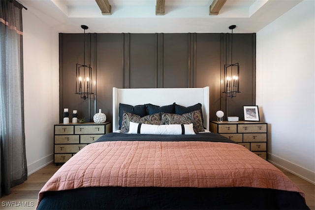 bedroom with beamed ceiling, baseboards, and light wood-style floors