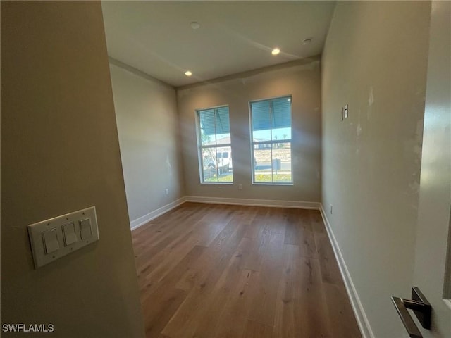 empty room with recessed lighting, wood finished floors, and baseboards