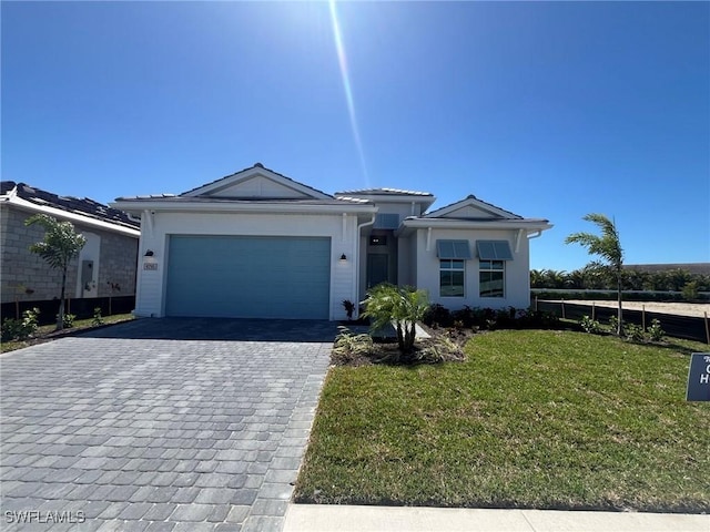 ranch-style house featuring a front lawn, decorative driveway, fence, and a garage