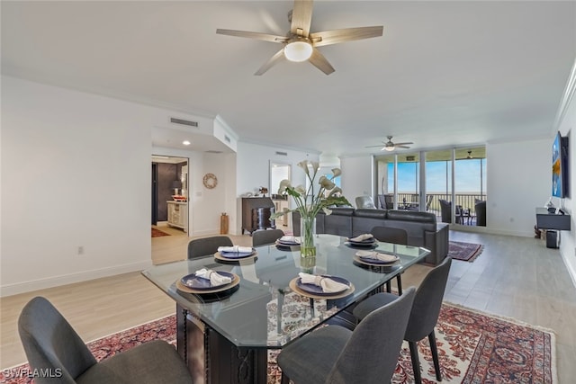 dining room with ceiling fan, crown molding, expansive windows, and light hardwood / wood-style floors