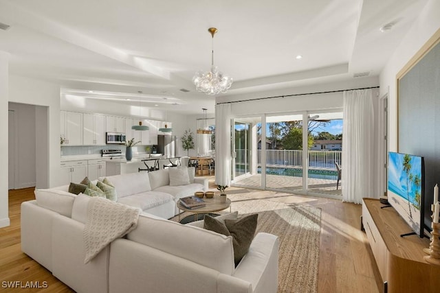 4584 W Alhambra Cir, Naples, FL 34103 - living room featuring a chandelier and light wood-type flooring