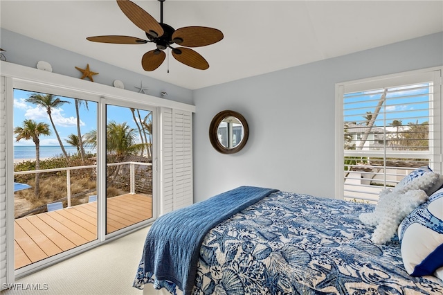 carpeted bedroom featuring multiple windows, ceiling fan, and a water view