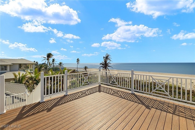 wooden terrace featuring a water view and a beach view