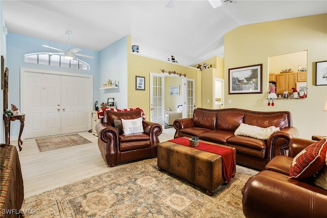 living room with vaulted ceiling, french doors, and light wood-type flooring