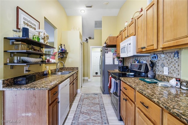 kitchen with sink, white appliances, dark stone counters, and decorative backsplash