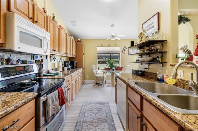 kitchen featuring ceiling fan, sink, light stone counters, and white appliances