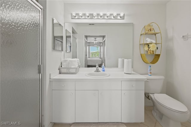 bathroom featuring ceiling fan, tile patterned flooring, toilet, a shower with door, and vanity