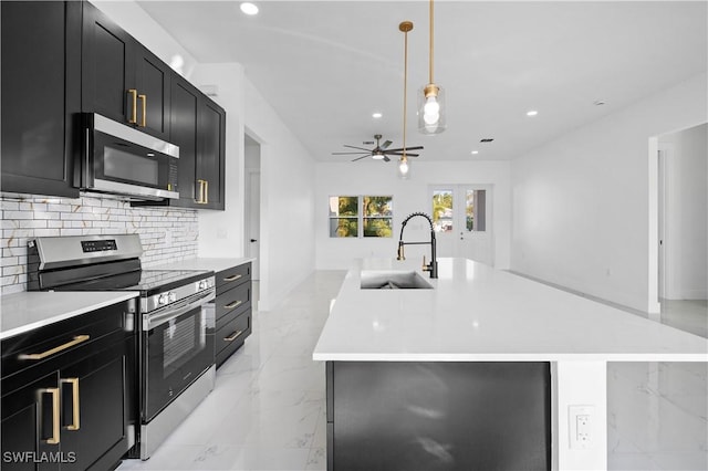 kitchen with backsplash, sink, hanging light fixtures, an island with sink, and stainless steel appliances