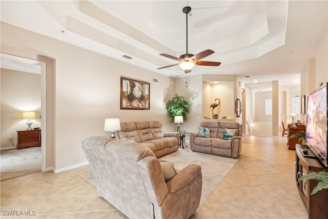 tiled living room featuring a tray ceiling and ceiling fan