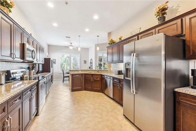 kitchen featuring appliances with stainless steel finishes, backsplash, hanging light fixtures, ceiling fan, and kitchen peninsula