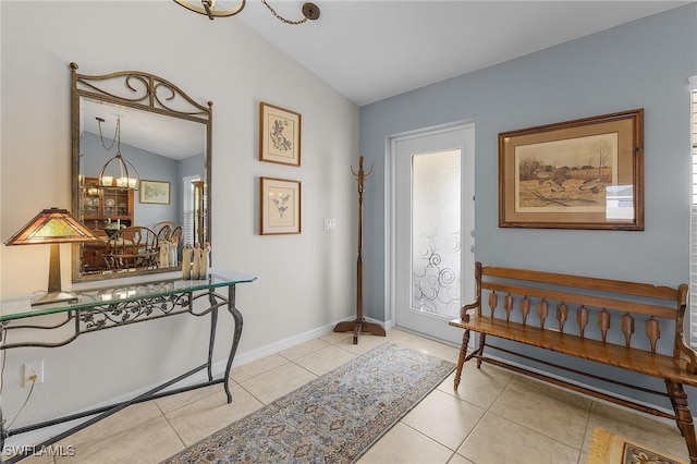 tiled entryway with lofted ceiling and a notable chandelier