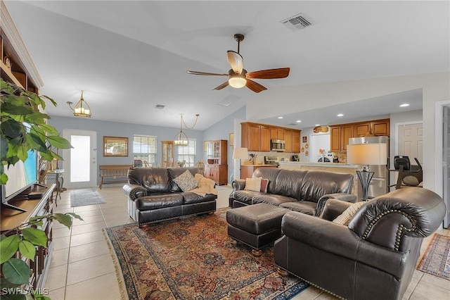 living room with ceiling fan with notable chandelier, light tile patterned flooring, and lofted ceiling