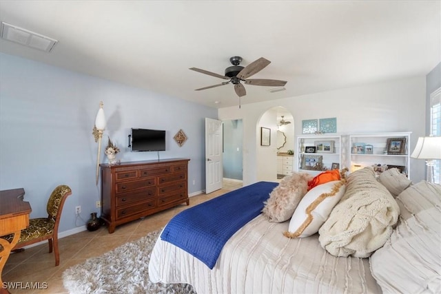 bedroom with light tile patterned floors, ensuite bath, and ceiling fan