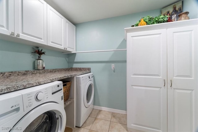 laundry area featuring washer and dryer, light tile patterned floors, and cabinets