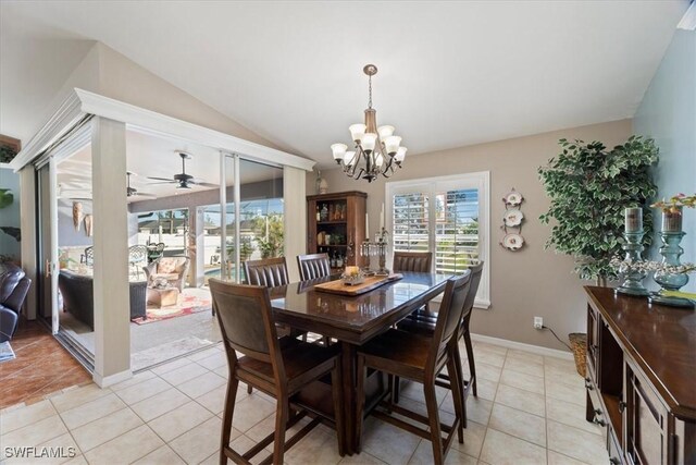 dining area with vaulted ceiling, light tile patterned flooring, and ceiling fan with notable chandelier