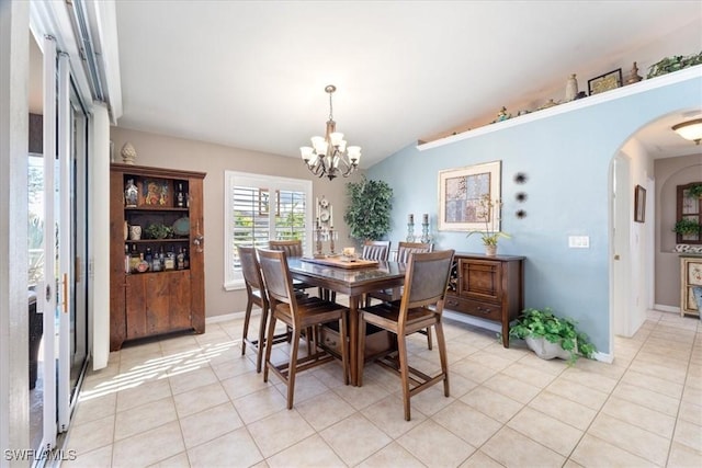 tiled dining space with vaulted ceiling and a chandelier