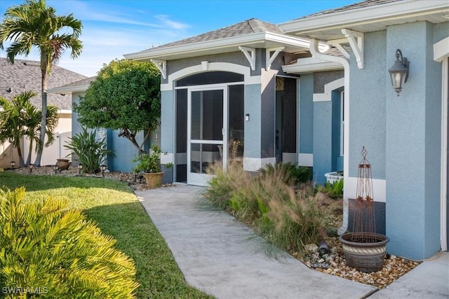 view of exterior entry featuring a lawn