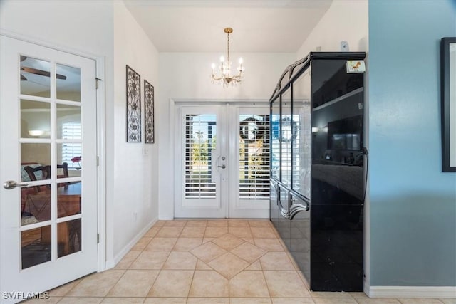 doorway with a notable chandelier, light tile patterned flooring, and french doors