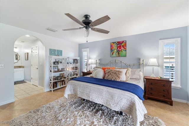 tiled bedroom featuring multiple windows, ensuite bathroom, and ceiling fan