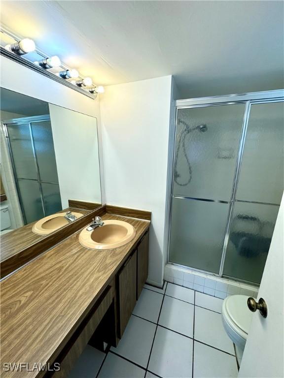 bathroom featuring toilet, vanity, tile patterned floors, and walk in shower