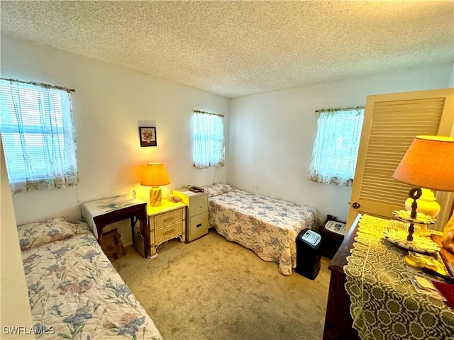 bedroom featuring light carpet, a textured ceiling, and multiple windows