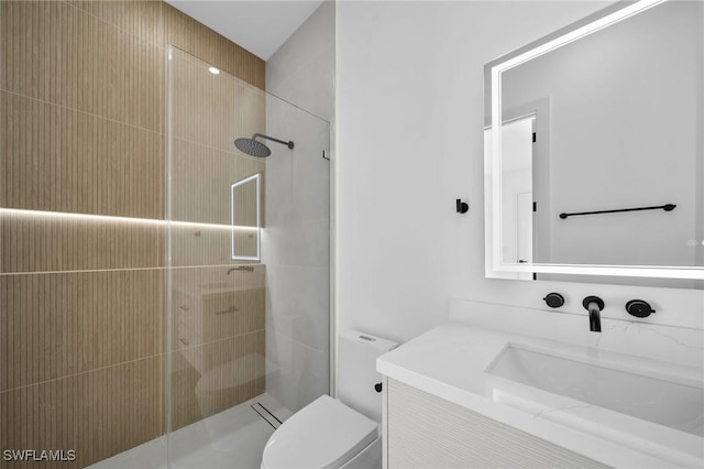 bathroom featuring a tile shower, vanity, and toilet