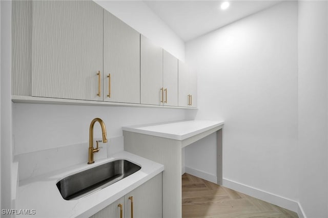 clothes washing area with sink and light parquet flooring