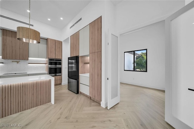 kitchen with decorative backsplash, black fridge, stainless steel double oven, pendant lighting, and light parquet flooring