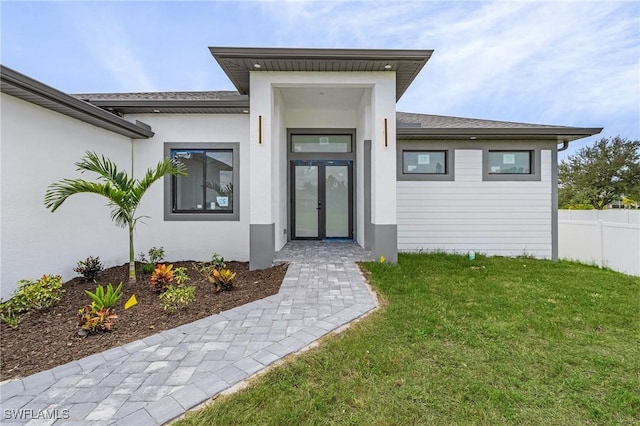 entrance to property featuring french doors and a lawn