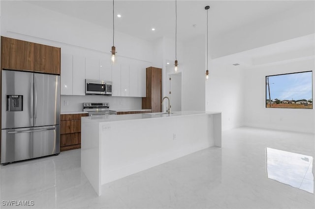 kitchen with white cabinets, a center island with sink, sink, hanging light fixtures, and appliances with stainless steel finishes