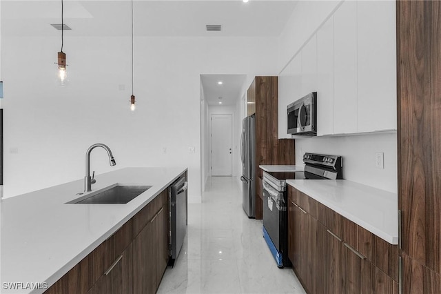 kitchen featuring appliances with stainless steel finishes, dark brown cabinetry, sink, decorative light fixtures, and white cabinets