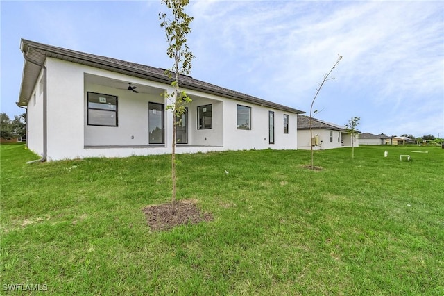 rear view of house with ceiling fan and a yard