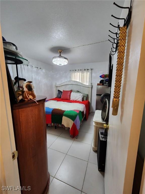 bedroom featuring light tile patterned flooring, a textured ceiling, and washer / clothes dryer