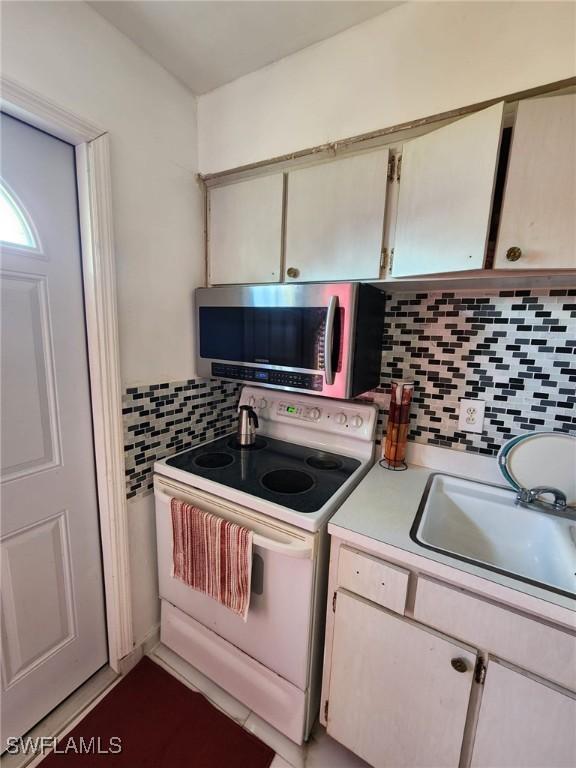 kitchen with electric stove, decorative backsplash, and sink