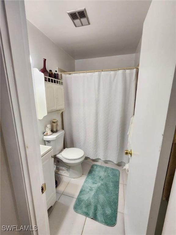 bathroom featuring tile patterned flooring, vanity, toilet, and walk in shower