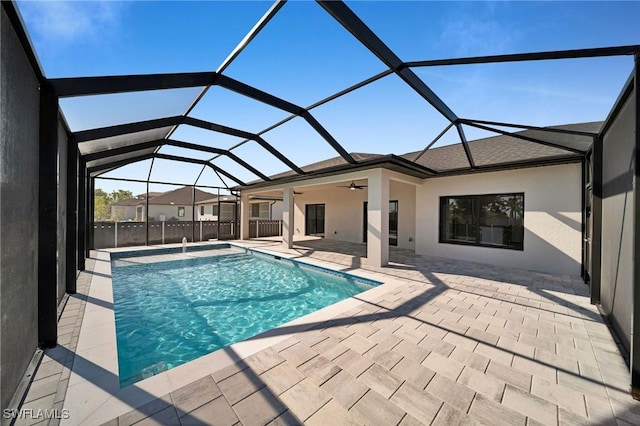 view of pool with glass enclosure, ceiling fan, and a patio