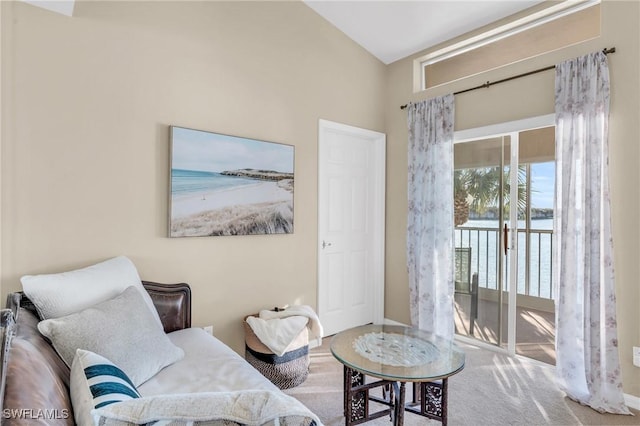 living area with carpet, a water view, a healthy amount of sunlight, and vaulted ceiling